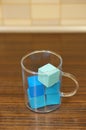 Glass mug with blue bath-coloring scented cubes on the table Royalty Free Stock Photo