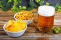 Glass mug of cold fresh golden beer with crackers and chips on wooden table, and branches of ripe hops Royalty Free Stock Photo