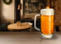 Glass mug with cold tasty beer on wooden table in pub, space for text Royalty Free Stock Photo