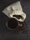 Glass mug with fresh black natural coffee, a bag with coffee grains and sprinkled grains of roasted coffee on a wooden table Royalty Free Stock Photo