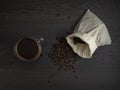 Glass mug with fresh black natural coffee, a bag with coffee grains and sprinkled grains of roasted coffee on a wooden table Royalty Free Stock Photo