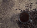 Glass mug with fresh black natural coffee, a bag with coffee grains and sprinkled grains of roasted coffee on a wooden table Royalty Free Stock Photo