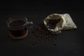 Glass mug with fresh black natural coffee, a bag with coffee grains and sprinkled grains of roasted coffee on a wooden table Royalty Free Stock Photo