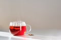 Glass mug with hot black tea on the table.