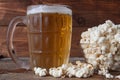 Glass mug of light beer with popcorn on wooden table, close up Royalty Free Stock Photo