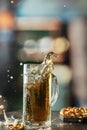 Glass mug of light cold beer with splash and flying drops with snacks on the table in pub Royalty Free Stock Photo