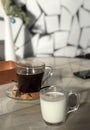 Glass mug of milk and americano coffee with dark sugar in cafe
