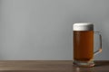 Glass mug of tasty dark beer on wooden table against grey background. Space for text Royalty Free Stock Photo