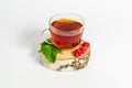 A glass mug of tea with berries of black currant and sugar cubes stands on a birch stump, isolated on a white background Royalty Free Stock Photo