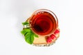 A glass mug of tea with berries of black currant and sugar cubes stands on a birch stump, isolated on a white background Royalty Free Stock Photo