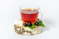 A glass mug of tea with berries of black currant and sugar cubes stands on a birch stump, isolated on a white background Royalty Free Stock Photo