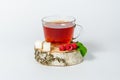 A glass mug of tea with berries of black currant and sugar cubes stands on a birch stump, isolated on a white background Royalty Free Stock Photo