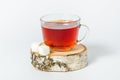 A glass mug of tea with berries of black currant and sugar cubes stands on a birch stump, isolated on a white background Royalty Free Stock Photo