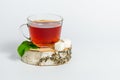 A glass mug of tea with berries of black currant and sugar cubes stands on a birch stump, isolated on a white background Royalty Free Stock Photo