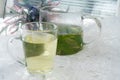 On the table In a glass mug and a teapot Fresh, floral, herbal tea made from mint and currant leaves in a mug