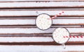Glass mugs, cups with hot chocolate, cocoa, marshmallows. Winter snow covered park bench. Striped red, white paper straws for Royalty Free Stock Photo
