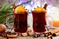 Glass mugs of hot mulled wine, Christmas tree branches and bokeh lights on background.