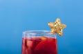 Glass of mulled wine decorated with a decorative gold star on a blue background