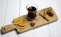 A glass of mulled wine on a wooden board with cinnamon sticks and orange slices. White wood background Royalty Free Stock Photo
