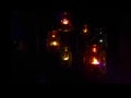 Christmas decoration in the form of colorful glass jars with burning candles inside on black background