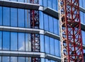Glass office building elevation detai. blue sky and ed steel tower crane reflecting Royalty Free Stock Photo