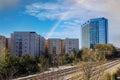 Glass office buildings and apartments along a side a set of railroad tracks with blue sky and powerful clouds and a rainbow Royalty Free Stock Photo