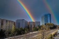 Glass office buildings and apartments along a side a set of railroad tracks with blue sky and powerful clouds and a rainbow Royalty Free Stock Photo