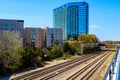 Glass office buildings and apartments along side a set of railroad tracks surrounded by lush green trees with  clear blue sky Royalty Free Stock Photo