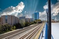 Glass office buildings and apartments along side a set of railroad tracks surrounded by lush green trees with powerful clouds Royalty Free Stock Photo