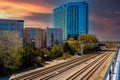 Glass office buildings and apartments along side a set of railroad tracks surrounded by lush green trees with  powerful red clouds Royalty Free Stock Photo