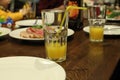 A glass of orange apricot yellow juice in a glass with a straw stands near a plate in the cafe`s restran. Lunch at the cafe Royalty Free Stock Photo