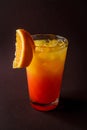 Glass of orange coctail with ice and slice of orange on elegant