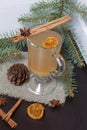 A glass of orange drink stands on a piece of linen. A slice of dried orange floats in it. Nearby are cinnamon sticks and dried Royalty Free Stock Photo