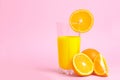 A glass with orange juice with the cut oranges on a pink background. Juicy color scale, pin up, pop up styles. Food for breakfast Royalty Free Stock Photo
