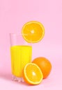 A glass with orange juice with the cut oranges on a pink background. Juicy color scale, pin up, pop up styles. Food for breakfast Royalty Free Stock Photo