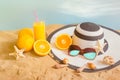 Glass of orange juice, hat, sunglasses and seashells on sand beach Royalty Free Stock Photo