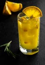 Glass orange juice with ice and slices orange with rosemary branch on black background Royalty Free Stock Photo