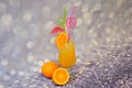 A glass of orange juice with ice and straws, stands on a shiny one, next to ripe citrus fruits Royalty Free Stock Photo