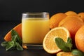 Glass of orange juice with mint, fresh oranges on a black background, citrus drink, close up Royalty Free Stock Photo