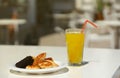 Glass of orange juice with plastic straw on white table in restaurant outdoor lounge zone Royalty Free Stock Photo