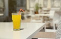 Glass of orange juice with plastic straw on white table in restaurant outdoor lounge zone Royalty Free Stock Photo