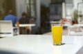 Glass of orange juice with plastic straw on white table in restaurant outdoor lounge zone Royalty Free Stock Photo