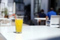 Glass of orange juice with plastic straw on white table in restaurant outdoor lounge zone Royalty Free Stock Photo