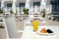 Glass of orange juice with plastic straw on white table in restaurant outdoor lounge zone Royalty Free Stock Photo