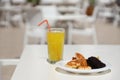 Glass of orange juice with plastic straw on white table in restaurant outdoor lounge zone Royalty Free Stock Photo