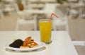 Glass of orange juice with plastic straw on white table in restaurant outdoor lounge zone Royalty Free Stock Photo