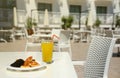 Glass of orange juice with plastic straw on white table in restaurant outdoor lounge zone Royalty Free Stock Photo