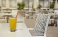 Glass of orange juice with plastic straw on white table in restaurant outdoor lounge zone Royalty Free Stock Photo