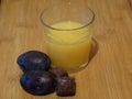 A glass of orange juice, plums and chocolate.