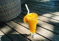 a glass of orange juice on the sandy beach. Fresh orange juice, fruits on sand with wooden background, summer concept Royalty Free Stock Photo